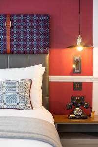 卡迪夫加的夫靛蓝酒店的一间卧室配有一张床和一张桌子上的闹钟
