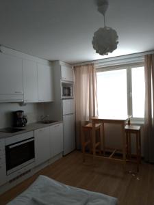 于韦斯屈莱Apartments Käyräkatu的厨房配有白色橱柜、桌子和窗户。