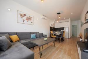 特罗吉尔Apartments Antica Trogir的客厅配有灰色的沙发和桌子