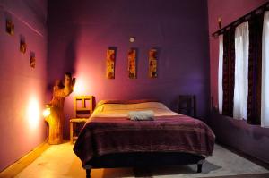 普尔马马尔卡Giramundo Hostel Purmamarca的紫色客房内的一间卧室,配有一张床