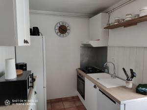 Rignacles gites de la bouldoire Renaissance的厨房配有白色橱柜、水槽和炉灶。