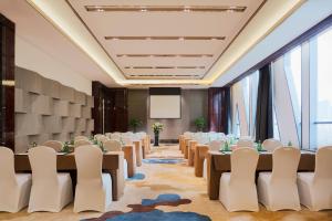 银川银川富力万达嘉华酒店 的一间会议室,配有桌椅和投影屏幕