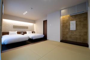 静冈Hotel Celeste Shizuoka的一间卧室设有两张床和一堵墙