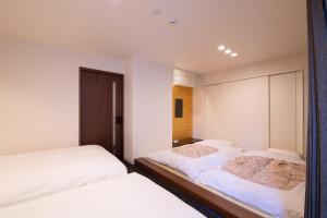 静冈Hotel Celeste Shizuoka的卧室内的两张床,配有白色的墙壁和白色的床单