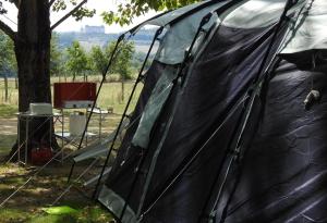 BoisseuilhCamping Belle Vue的坐在树旁田野上的黑色帐篷