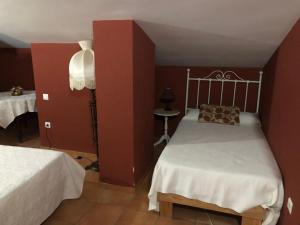 马尔帕尔蒂达德卡塞雷斯Hostal La Caballeriza的一间卧室设有两张床和红色的墙壁