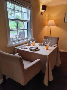 阿多奈格 Ardeonaig Hotel & Restaurant的一张桌子、白色的桌布、椅子和窗户