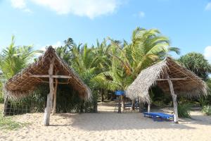 坦加拉唐加勒孤滩度假住宿加早餐旅馆的海滩上的两把草伞和一张蓝色长椅