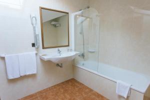 里博雷多奥卡斯特罗酒店的一间带水槽、淋浴和镜子的浴室