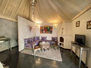 马拉喀什Eden Lodges & SPA的客厅配有紫色沙发和电视
