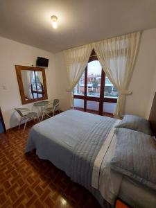 帕拉卡斯El Capricho Paracas的一间卧室配有一张床、一张桌子和一个窗户。