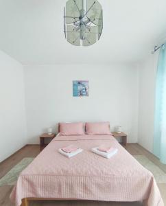 Ličko Petrovo SeloGuesthouse D&D的一间卧室配有一张带粉色毯子和时钟的床。