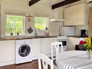 Stenhamra4 person holiday home in STENHAMRA的厨房配有洗衣机和桌椅