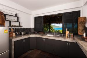 涛岛柯岛高地精品别墅酒店的一间厨房,配有黑色橱柜和大窗户