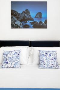 阿纳卡普里Casetta Caprile的一张带蓝色和白色枕头的床和一张照片