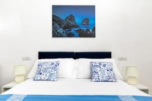 阿纳卡普里Casetta Caprile的卧室配有白色床和蓝色及白色枕头