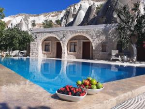 格雷梅Seven Rock Cave Hotel的游泳池畔的度假胜地,有两碗水果