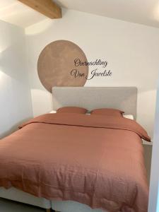 恩斯赫德Overnachting Vanjewelste的卧室配有一张挂有墙上标志的床