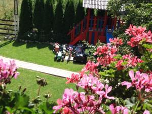 布朗Vila Deni的一座种有粉红色花卉的花园和一个游乐场