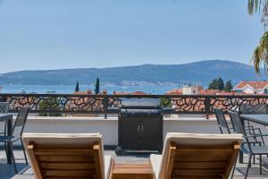 蒂瓦特Moderna Luxury Apartments with HEATED pool的一个带椅子和阳台的庭院内的烧烤架
