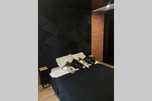 罗兹Apartament Manufaktura z bezpłatnym parkingiem的一间卧室设有黑色的墙壁和一张带枕头的床。