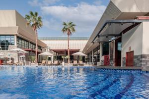 迪拜Jumeirah Creekside Dubai的棕榈树建筑前的游泳池
