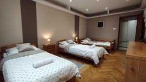 韦伦采Lux Apartman Velence的一间卧室配有两张带白色床单和木地板的床。