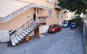 热那亚博卡西纳酒店的一座公寓楼,设有楼梯,停车场内有车辆停放