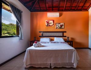 莫罗圣保罗Areia Branca Apart Hotel的一间卧室配有一张带橙色墙壁和窗户的床