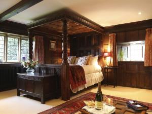 布罗德韦Abbots Grange Manor House的一间卧室配有一张床和一张桌子及一瓶葡萄酒