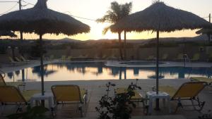 法里拉基夏日酒店的一个带桌椅和遮阳伞的游泳池