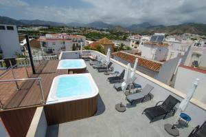 内尔哈NERJA-CENTRO-JACUZZI- MIRADOR DE LA ERMITA- Adults Recommended的一个带热水浴缸和椅子的阳台以及一个游泳池