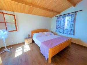 Gornji HumacVala Hrvaska Robinson的一间卧室设有一张床、一个窗口和风扇