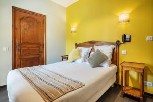 萨尔拉拉卡内达Hôtel La Couleuvrine Sarlat Centre Ville的一间卧室设有一张黄色墙壁的大床