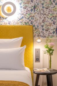 巴黎加蓬酒店的一间卧室配有黄色床头板和花卉壁纸