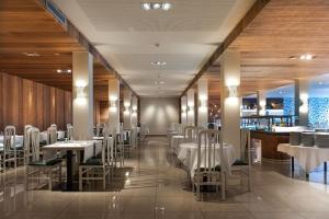 马尔格莱特德玛Hotel Rosa Nàutica的一间设有白色桌椅的餐厅和一间酒吧