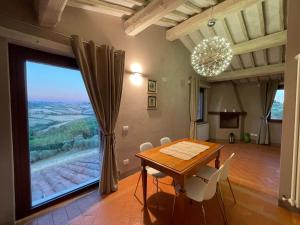 皮恩扎Poggio ai Gelsi的一间带桌子和大窗户的用餐室