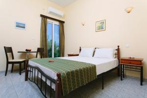 卡梅纳维洛拉Hotel Loula Rooms and Apartments的一间卧室配有一张床、一张桌子和一个窗户。