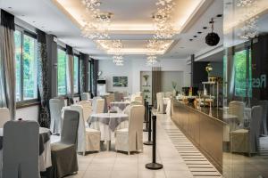 科孚镇阿里昂酒店的餐厅设有白色的桌椅和窗户。