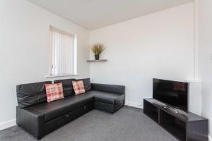 布莱克浦Cherry Property - Mulberry Suite的客厅配有黑色真皮沙发和平面电视。