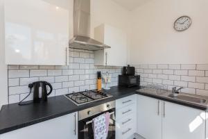 布莱克浦Cherry Property - Mulberry Suite的厨房配有白色橱柜和炉灶烤箱。
