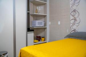 维索萨-杜塞阿拉Flat da Vila的一间卧室配有黄色的床和微波炉