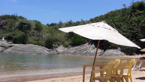 瓜拉派瑞Apartamento a Beira Mar em Setiba Guarapari的海滩上的桌椅和遮阳伞