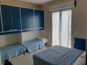 里米尼Hotel Giannini的配有蓝色橱柜和窗户的客房内的两张床