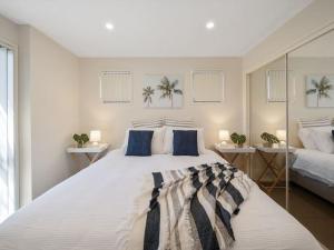 文森提亚Portside at The Arc by Experience Jervis Bay的卧室配有带蓝色枕头的大型白色床