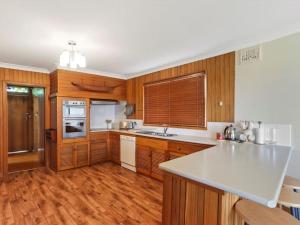 文森提亚Summer Breeze by Experience Jervis Bay的厨房配有木制橱柜和白色台面