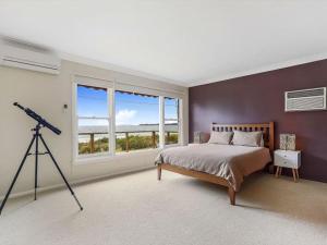 文森提亚Summer Breeze by Experience Jervis Bay的一间卧室配有一张大床和一个望远镜