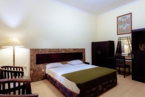 外南梦Hotel Mahkota Plengkung by ecommerceloka的一间卧室配有一张床、一张桌子和一把椅子