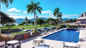 凯恩斯Cairns Harbourside Hotel的一个带桌椅的度假村游泳池,并种植了棕榈树