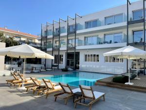 帕拉利米尼Mythical Sands Resort - Good Vibes Apartment的大楼前的带椅子和遮阳伞的游泳池